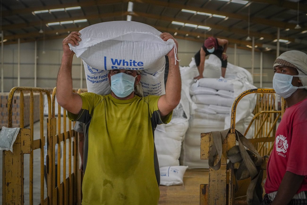 A worker at a WFP warehouse in Sana’a offloads bags of humanitarian assistance. ©WFP/Mohammed Awadh