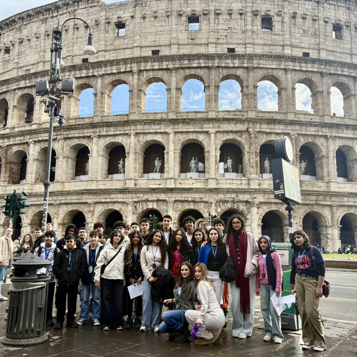 A group of students poses in front of the Colosseum in Rome. They are ...
