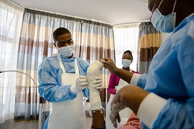 Physiotherapist Dominic putting a fresh cast on Tamia's right leg during outpatient clinic.