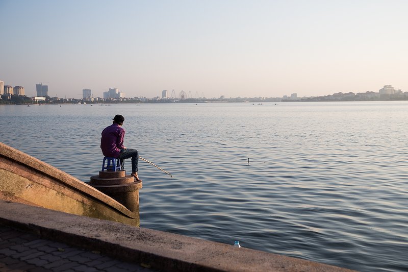 A fisherman patiently waits for a nibble on largest lake in the city.