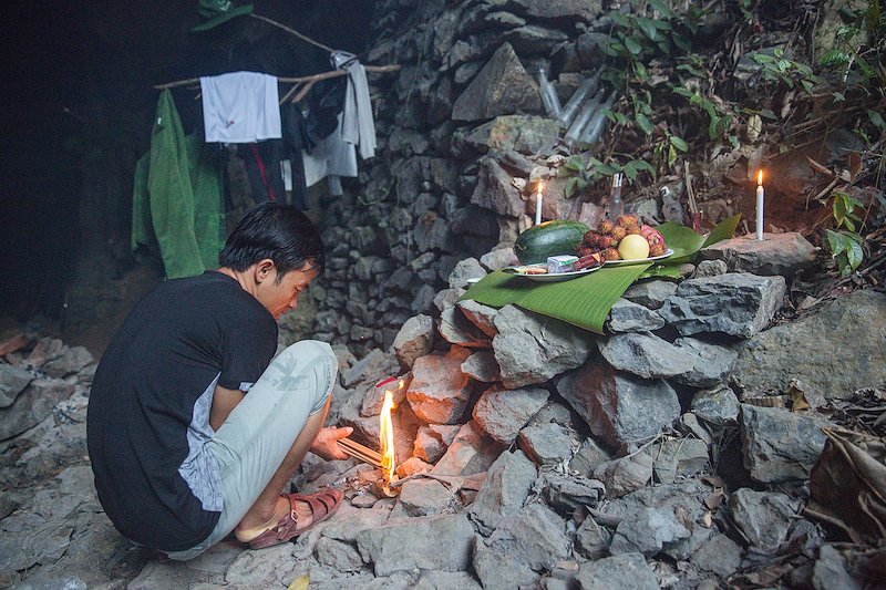 Lighting incense before completing a small prayer over the votive offerings.