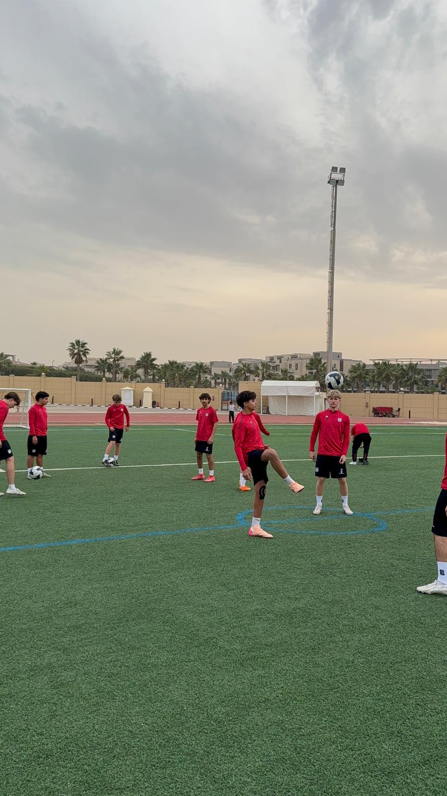 A group of young soccer players in red jerseys practice on a green ...