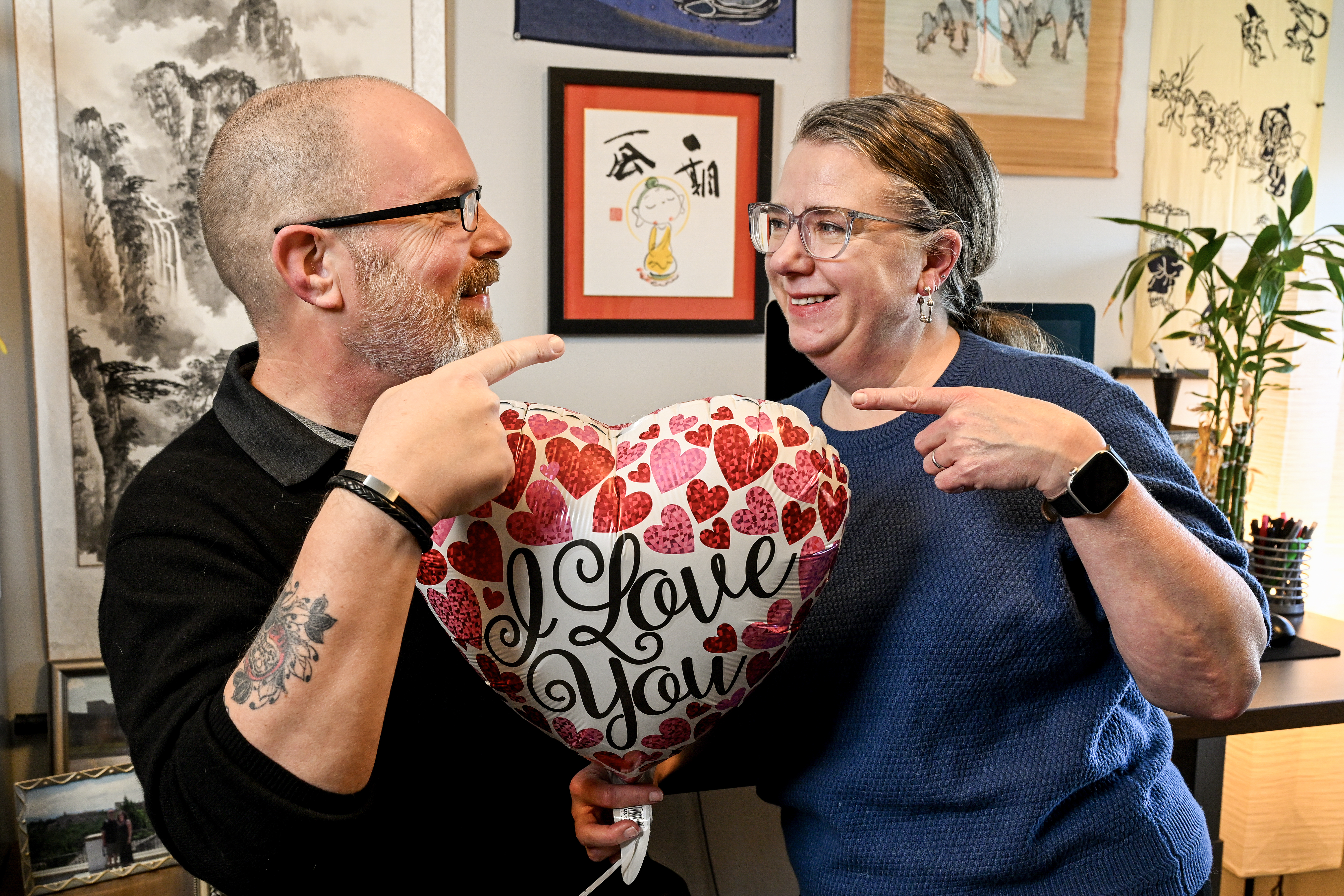 Alyssa Beall and Alex Snow hold a heart-shaped balloon that reads