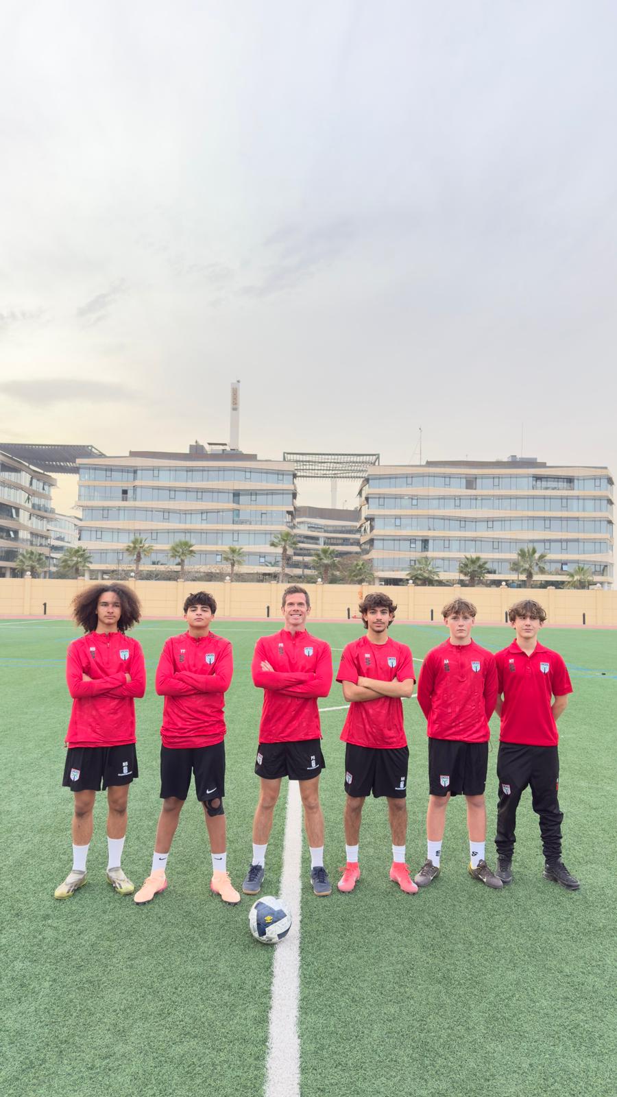 Soccer team stands on a green field with a soccer ball, wearing red ...