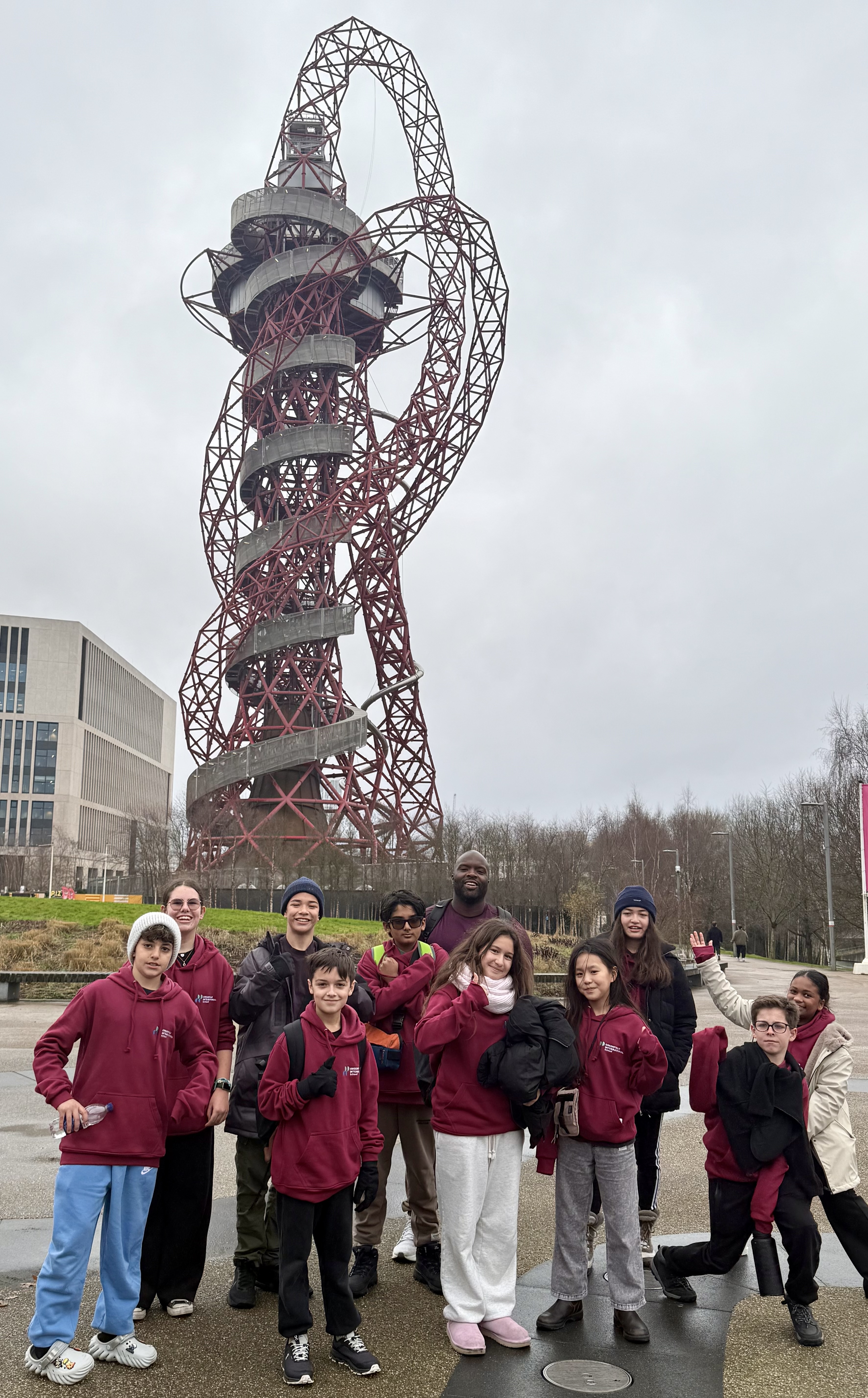 A group of students and a chaperone pose in front of the ArcelorMittal ...