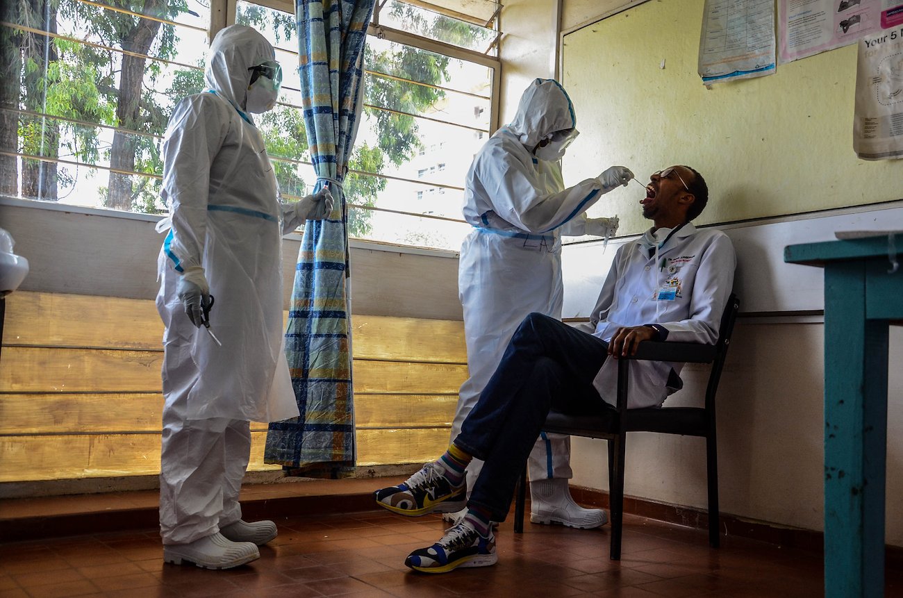 Health officers Audry Rotich and Joyce Kidogo take swab samples from a patient for Covid-19 during mass staff testing at Kenyatta National Hospital in Nairobi. Photo: Shutterstock/Peter Okiddy