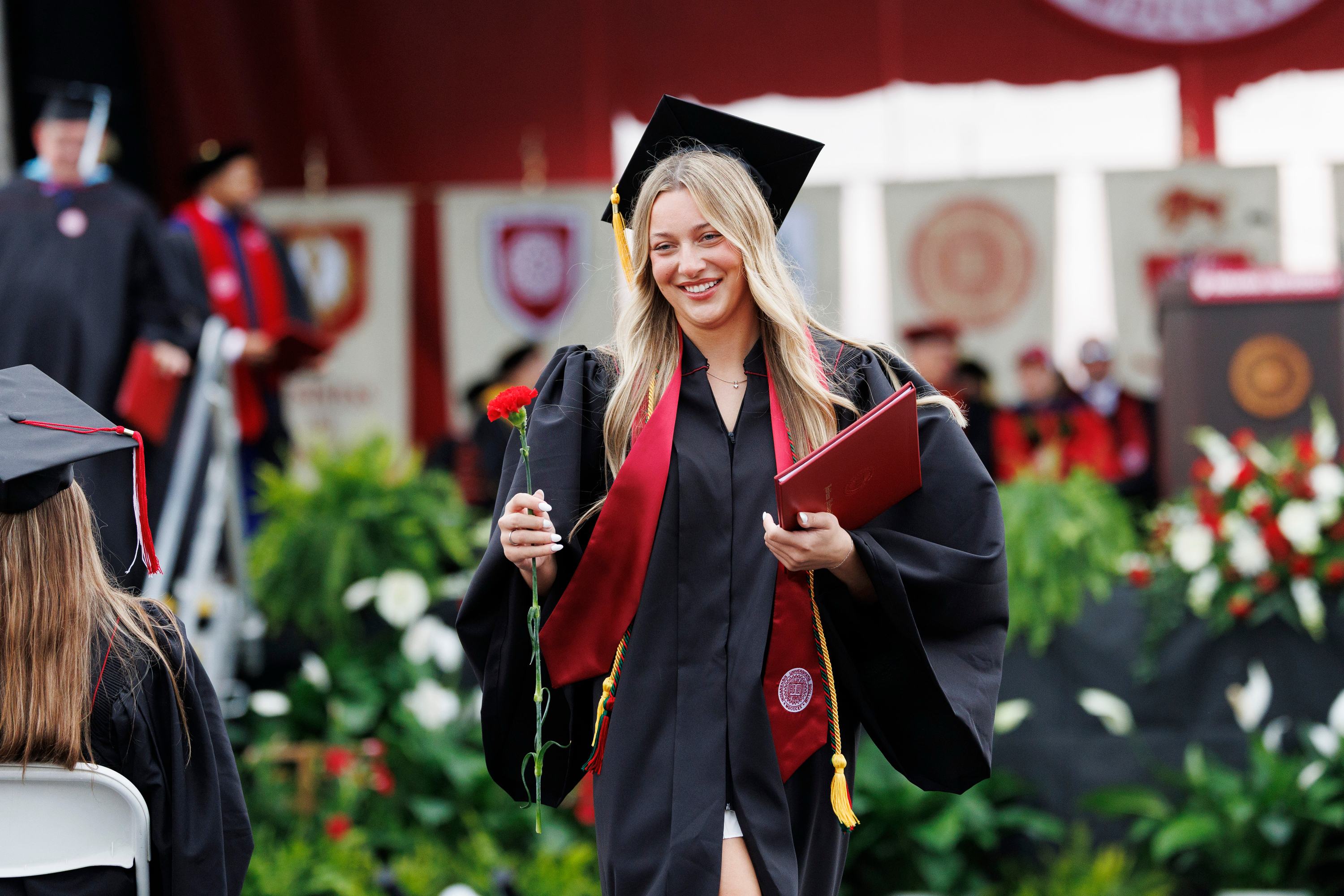 A graduate carries a rose after receiving a diploma cover during the IU ...