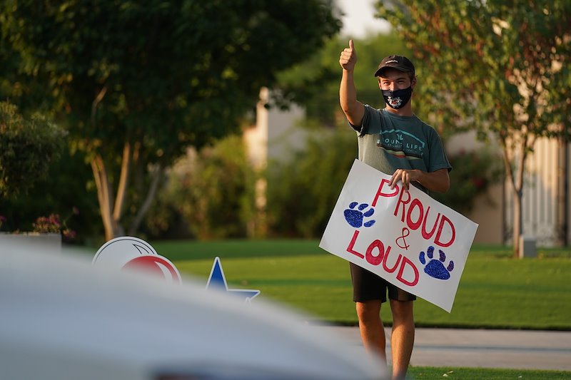 A student acknowledges car passengers during the New Student Convocation parade