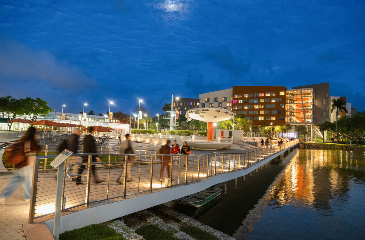 Students stroll across a bridge at dusk on the University of Miami ...