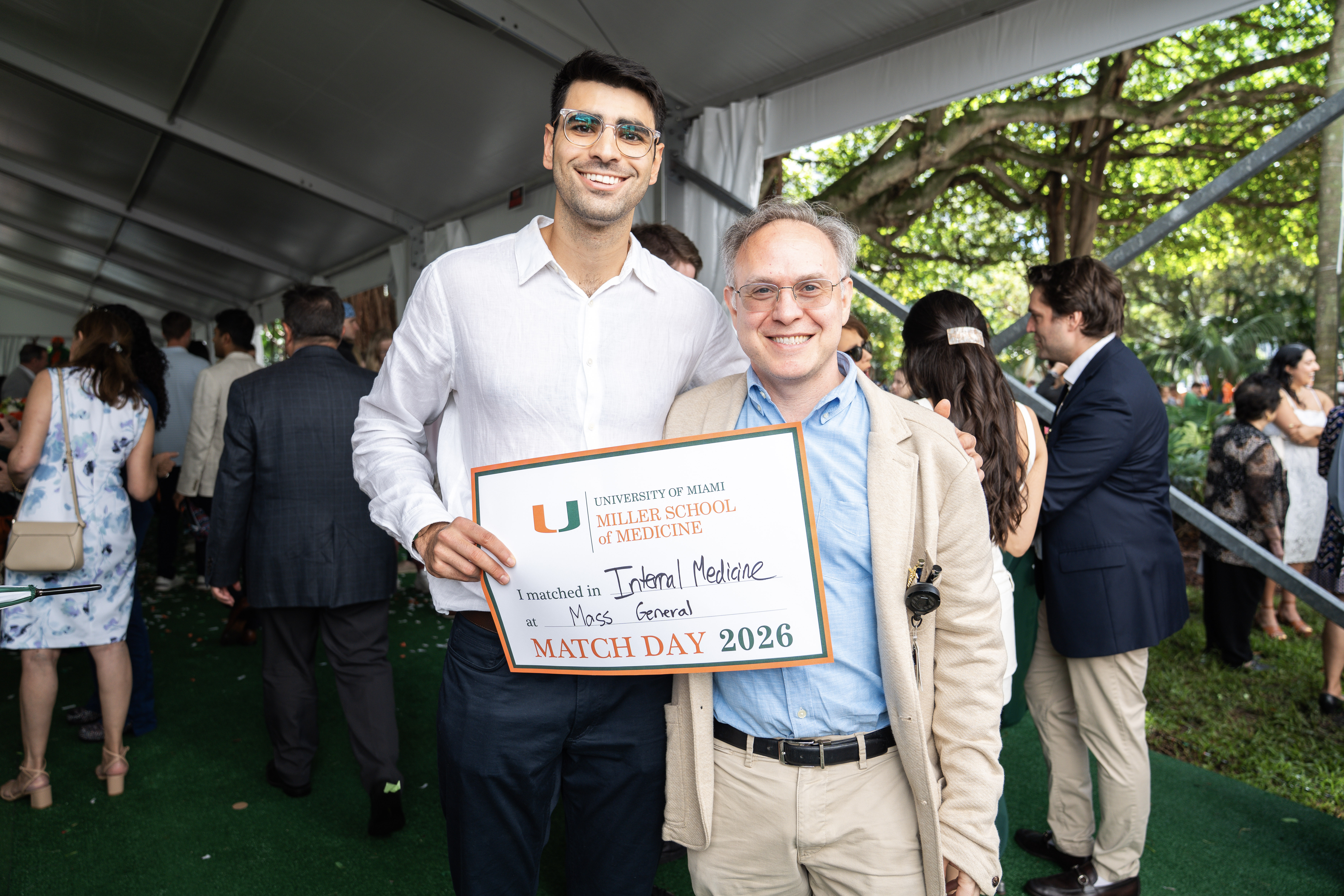 Two smiling men hold a sign reading