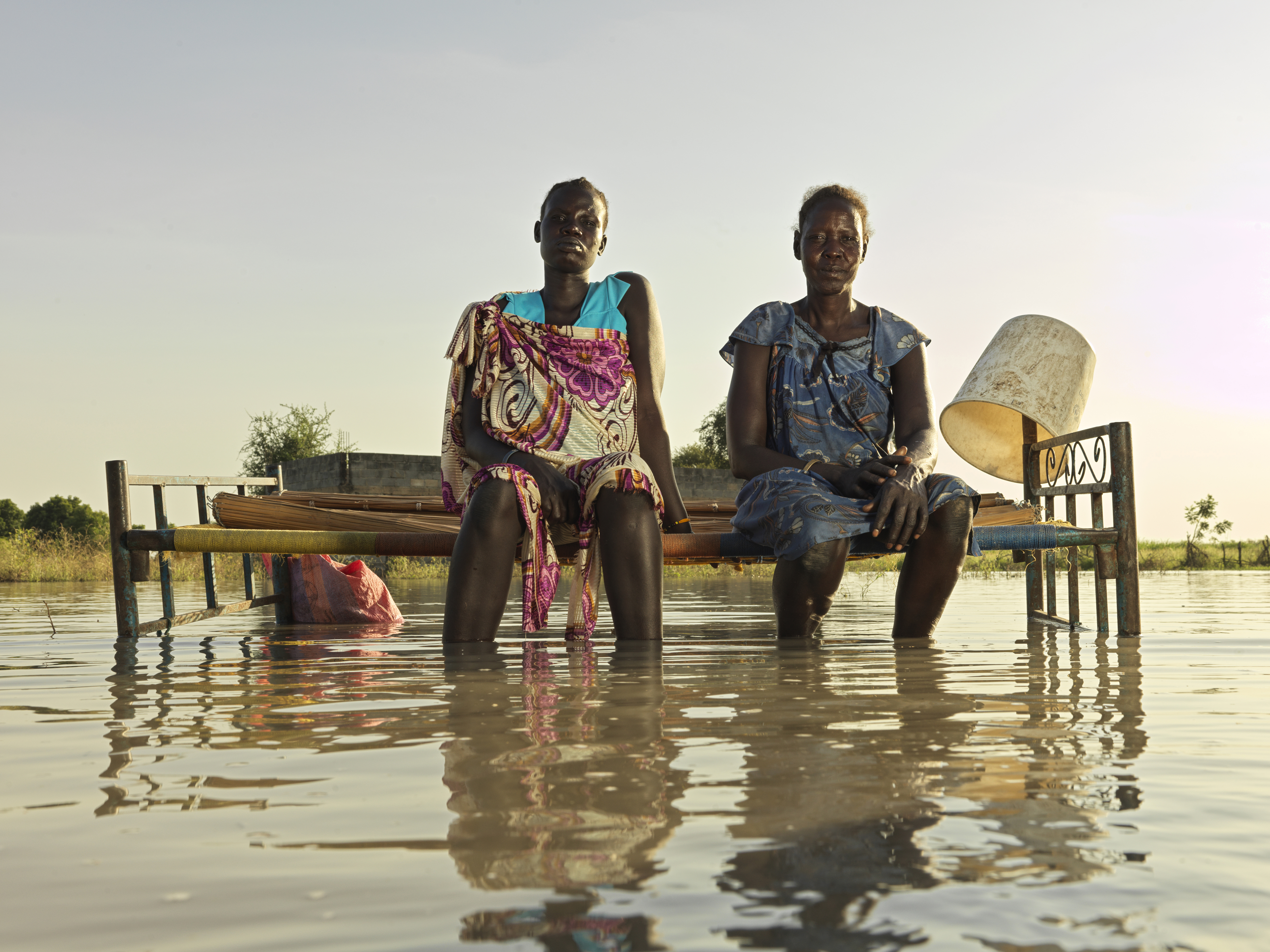 Nyagout and her daughter on a bed in floodwater in Wangchot village ...