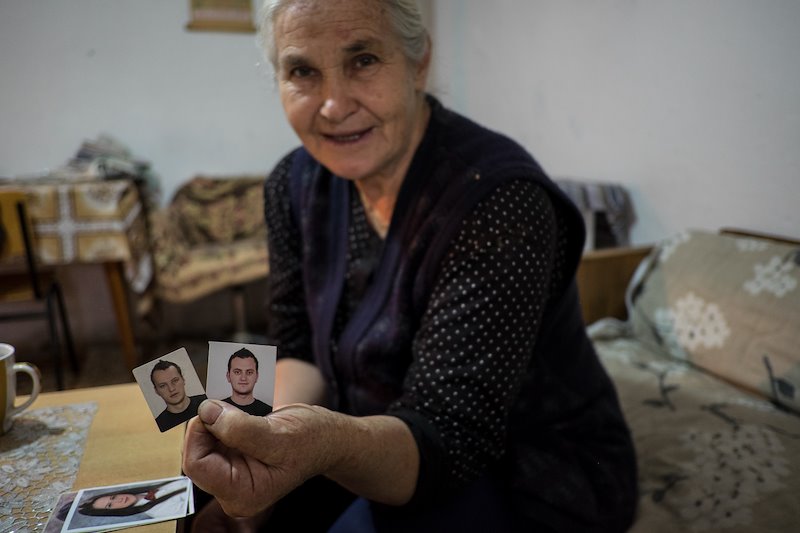 Elena Sumracka holds photos of her grandsons, who have gone elsewhere to find work.