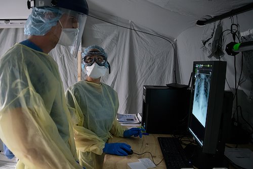 Stephanie, a physician's assistant, reviews patient x-rays with Lucca, a translator who is in medical school, as she orients him to the SP field hospital in Cremona.