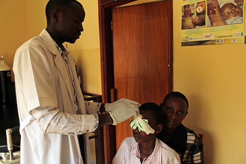 The nurse removes Reymond's bandages after having cataract surgery on both of his eyes.