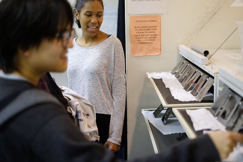 Kai Lu (’17) and Nia McIntosh ('18) admire the work of their classmates as the students’ final portraits are displayed.