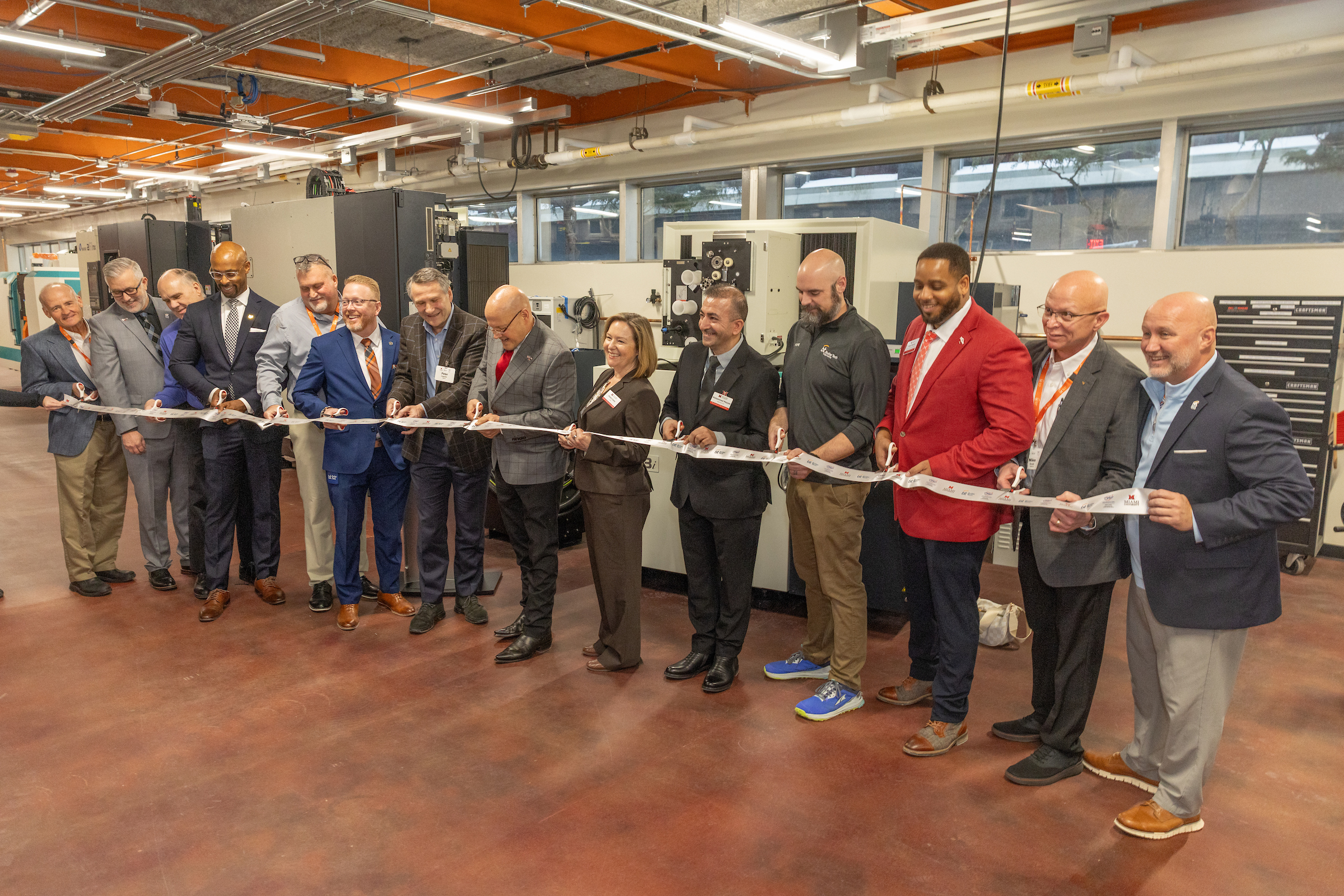 A group cuts a ribbon at the MU AM HUB dedication. Eleven people in ...