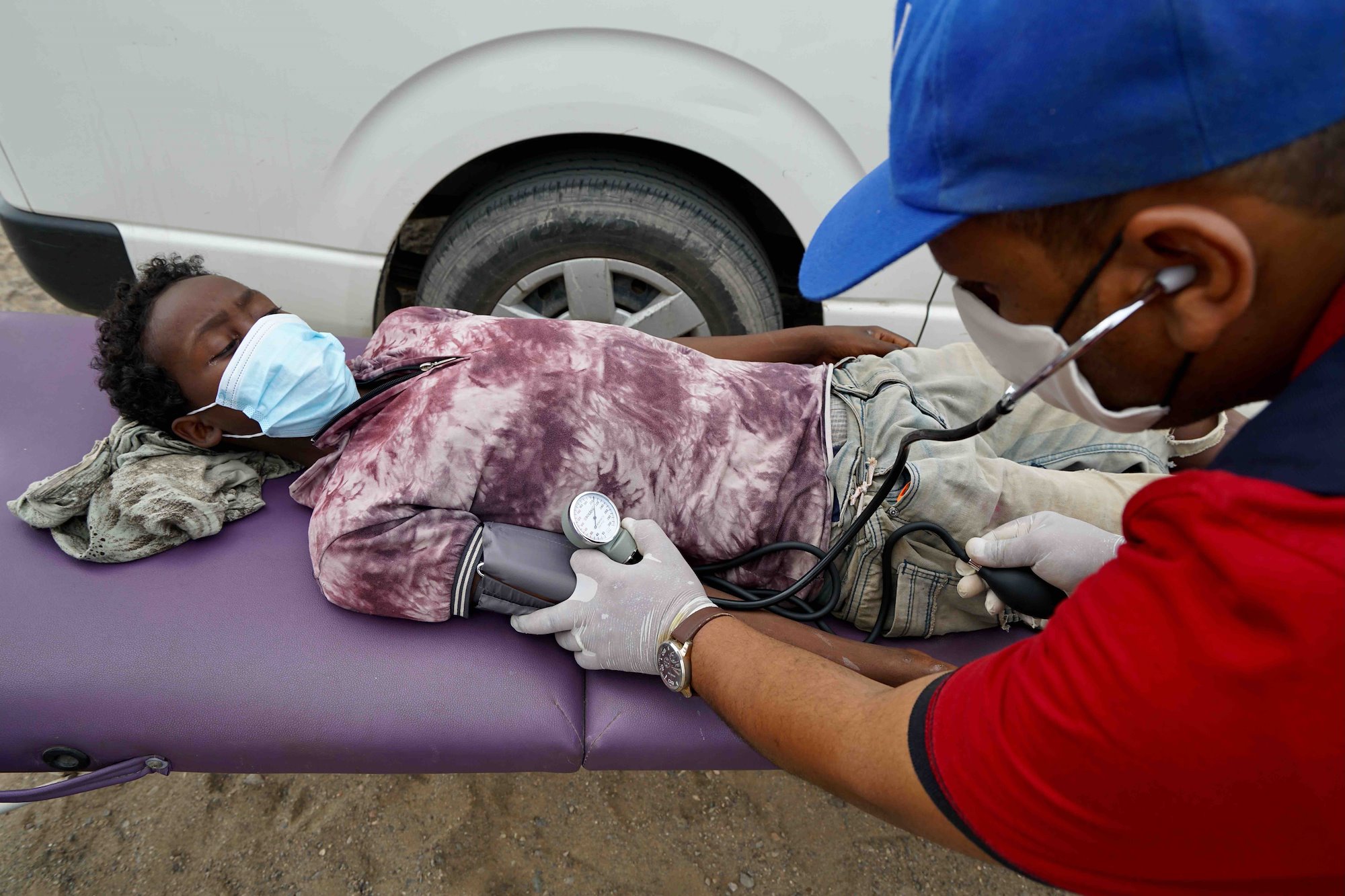 An Ethiopian migrant lies on a gurney used by IOM mobile doctors to check people who have recently arrived.