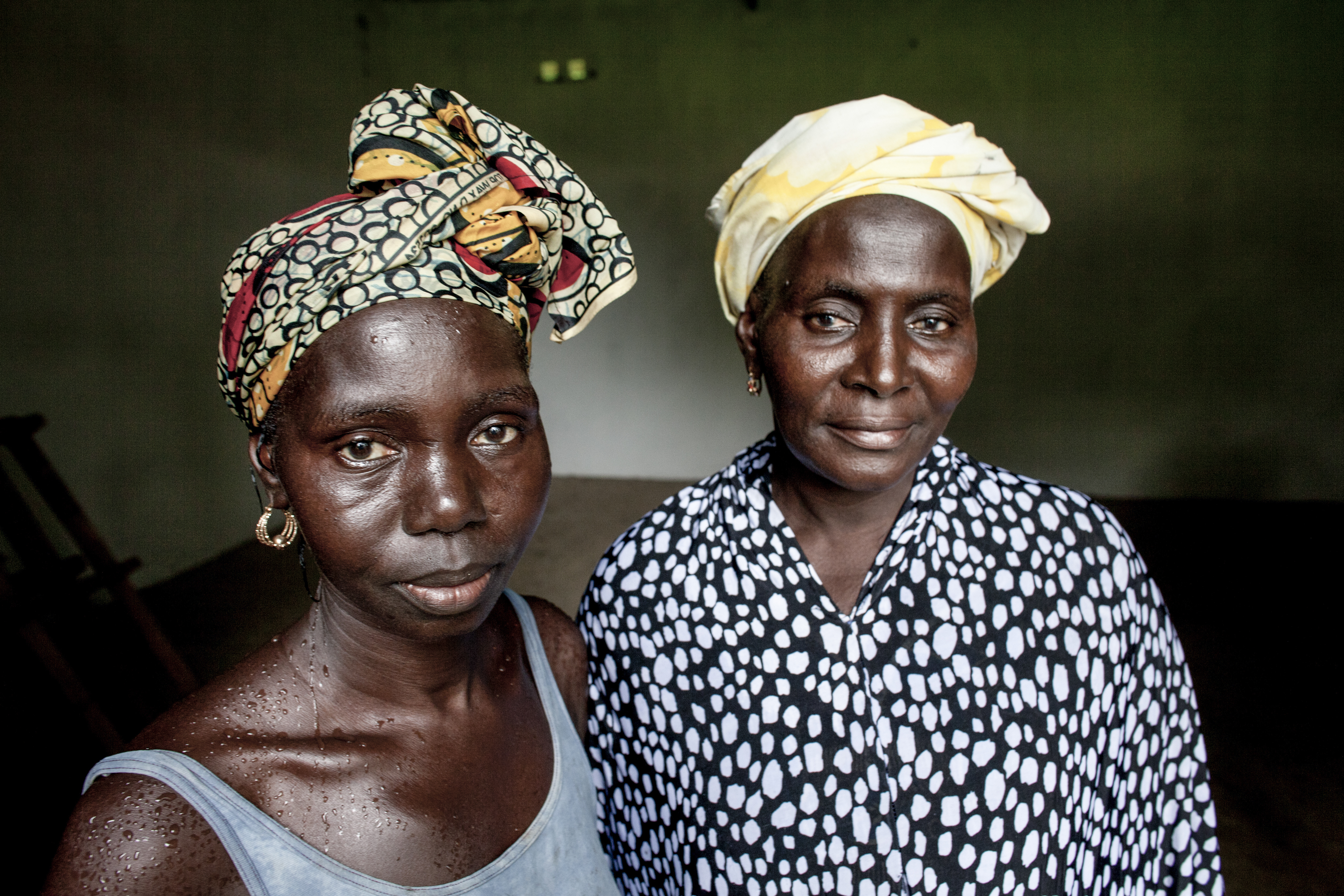 Naato Dibba &amp; Fatou Fatajo shelter from the rain in the Salikene Seed &amp; Cereal Bank safestore against poor harvests. © Jane Hahn / ActionAid