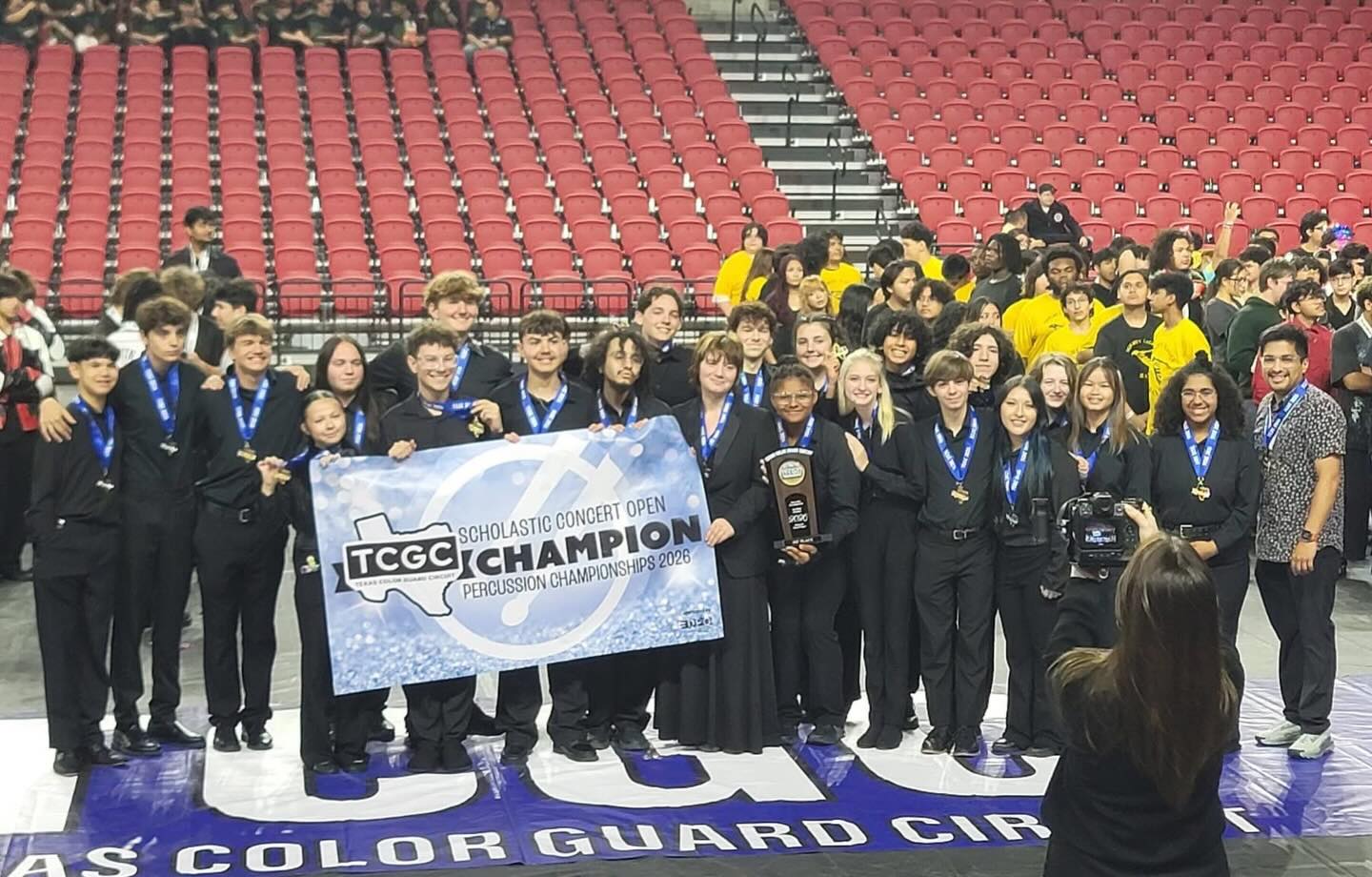 A percussion group poses with their trophy and banner that reads