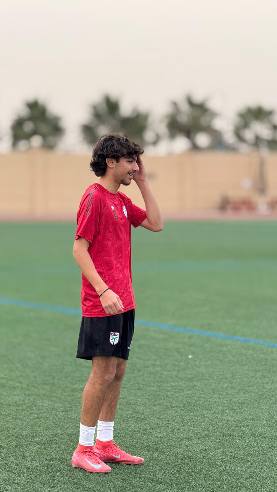 Young soccer player stands on the field, hand on head, looking off to ...