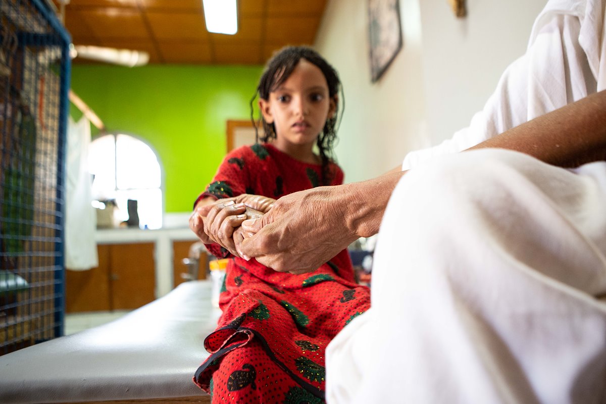 This girl is working on physical therapy for her burned hand with her grandfather.