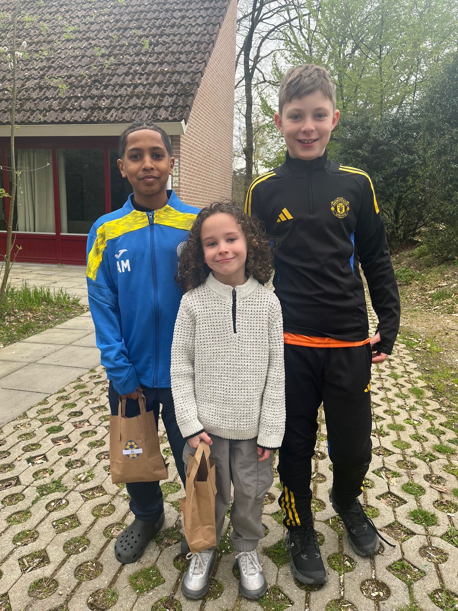 Three young Fletcher Moss Rangers team members stand smiling outdoors ...