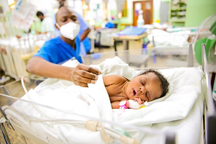 A baby sound asleep in the ward as our nurse closely monitors.