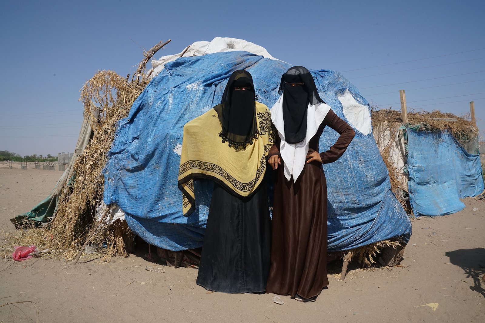 Two recently displaced Yemeni women in front of their shack in a desert camp in Aden, south Yemen. Credit: UNOCHA/Giles Clarke