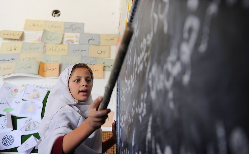 A young student reads from a blackboard  in Kabul.