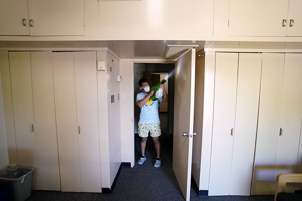 A student sprays disinfectant in the dorms in preparation of the Fall 2020 semester.
