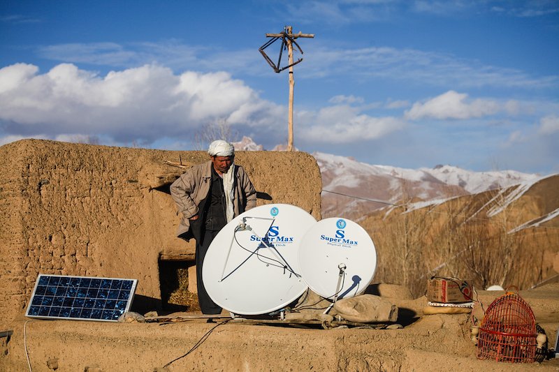An Afghan farmer sets up a satellite TV powered by solar panels on the roof of his home in Bamyan.