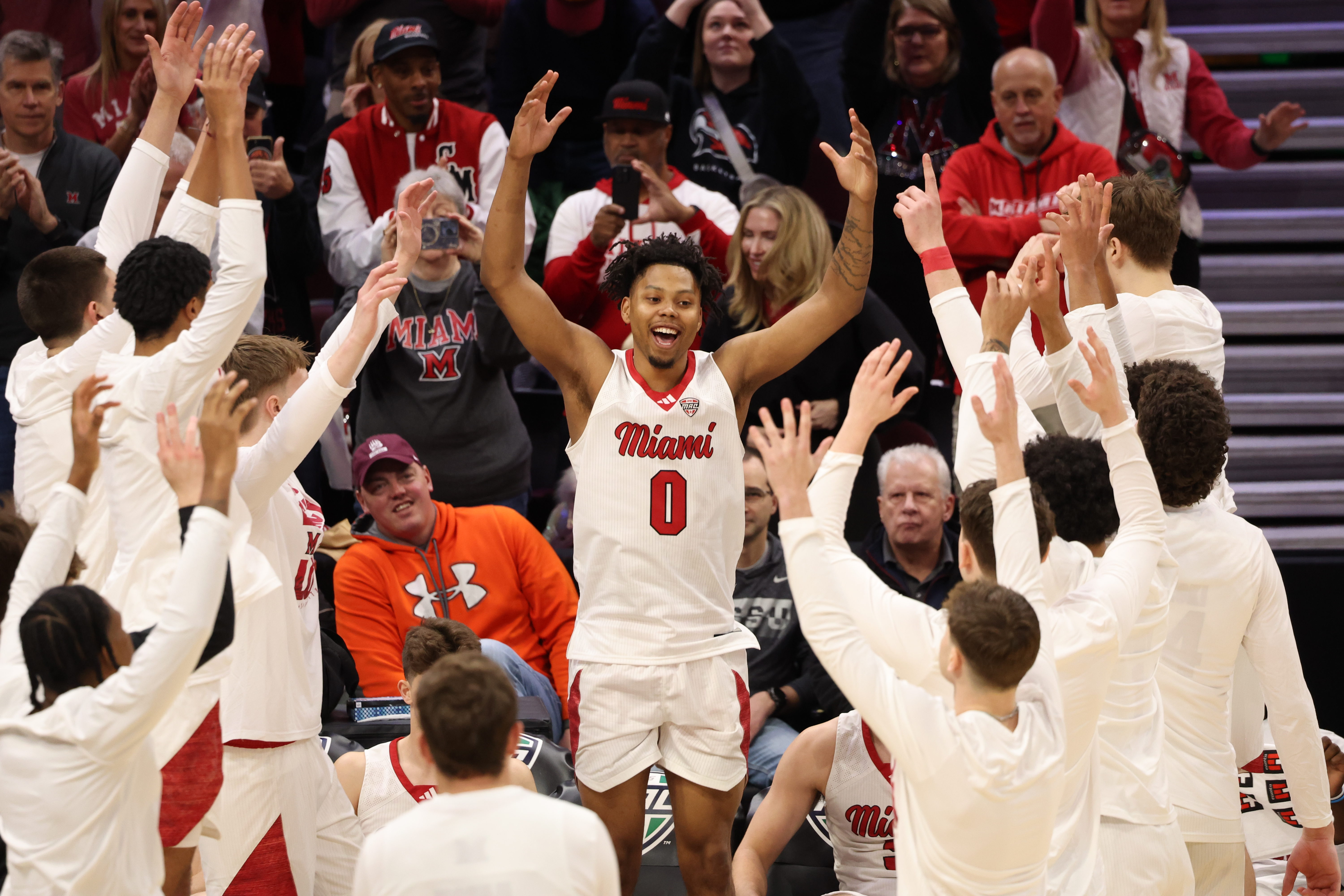 Miami player with arms raised is mobbed by teammates on the court. The ...