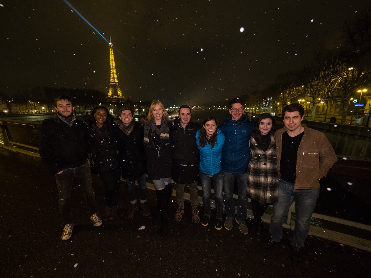 Students celebrate the conclusion of the staff ride in Paris, posing for photos in front of the Eiffel Tower in the snow.
