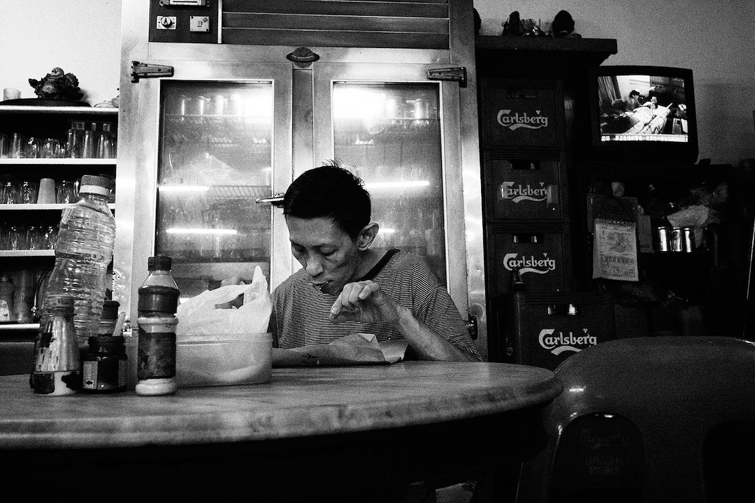 younger shi having lunch in between serving coffee. it will take him at least 5 seatings to finish his meal.