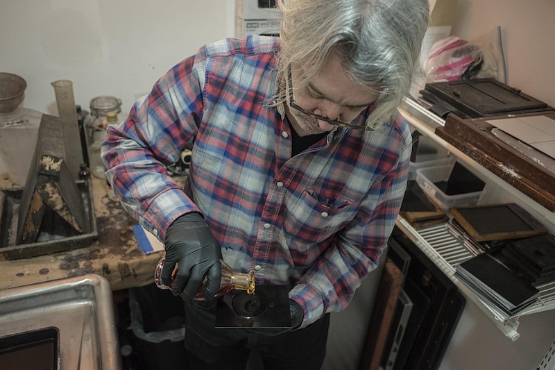 Geoffrey Berliner pouring the collodion on the fresh plate.