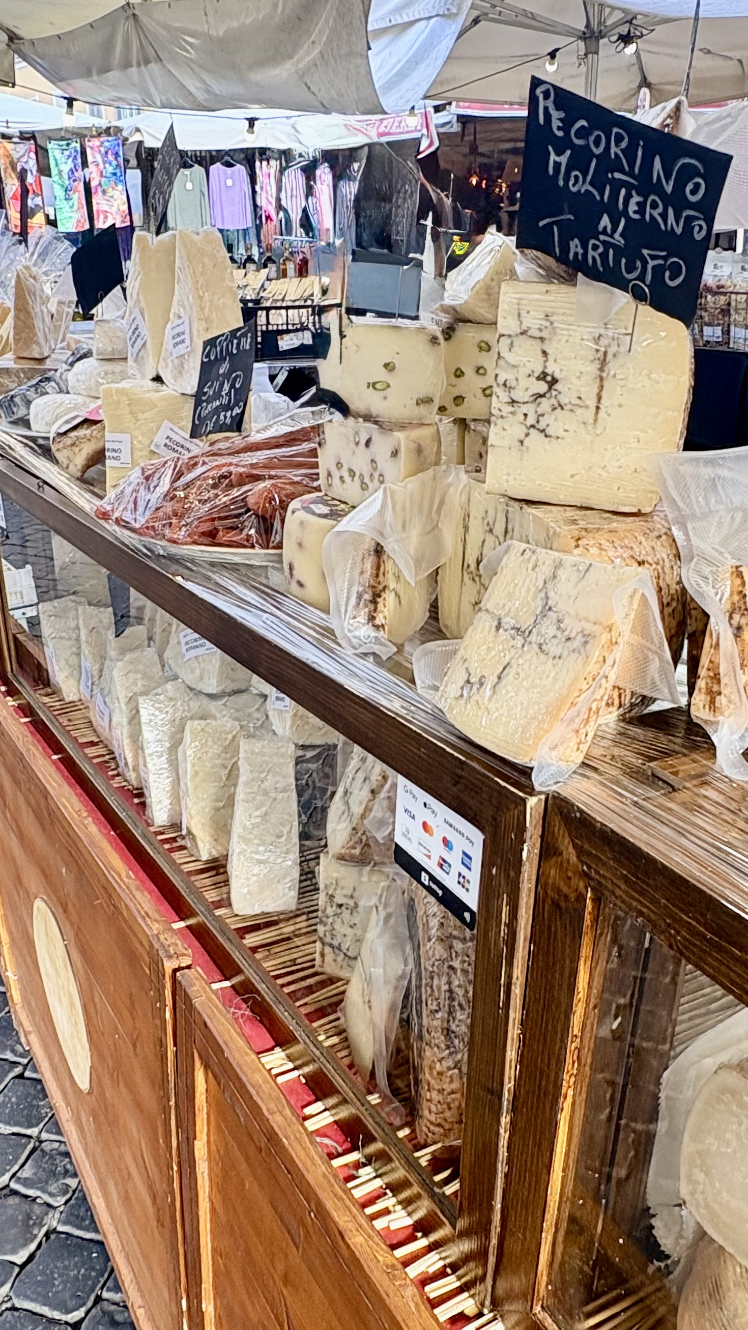 Cheese stand displays various Italian cheeses under a white tent. A ...