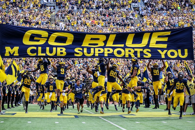 Michigan runs out of the tunnel and touches the banner for the first time in the 2016 season.
