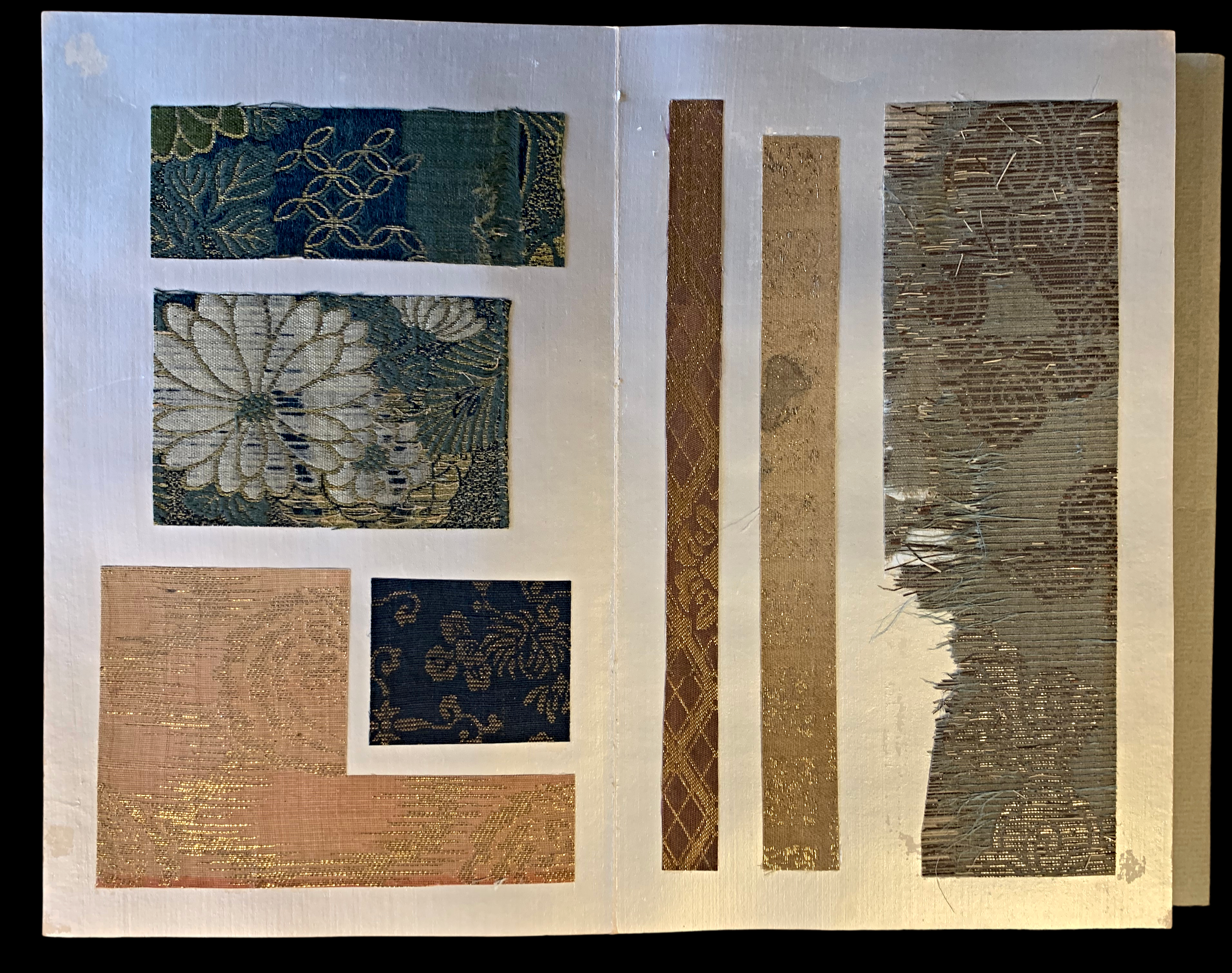Open catalogue displays mounted Japanese textile samples. The left page ...