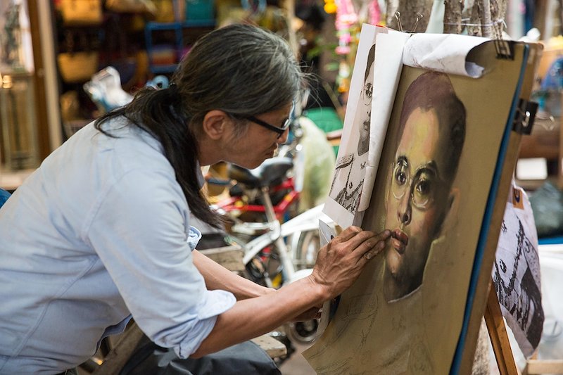 An artist at Chatuchak Weekend Market paints a portrait of a young King Bhumibol Adulyadej.