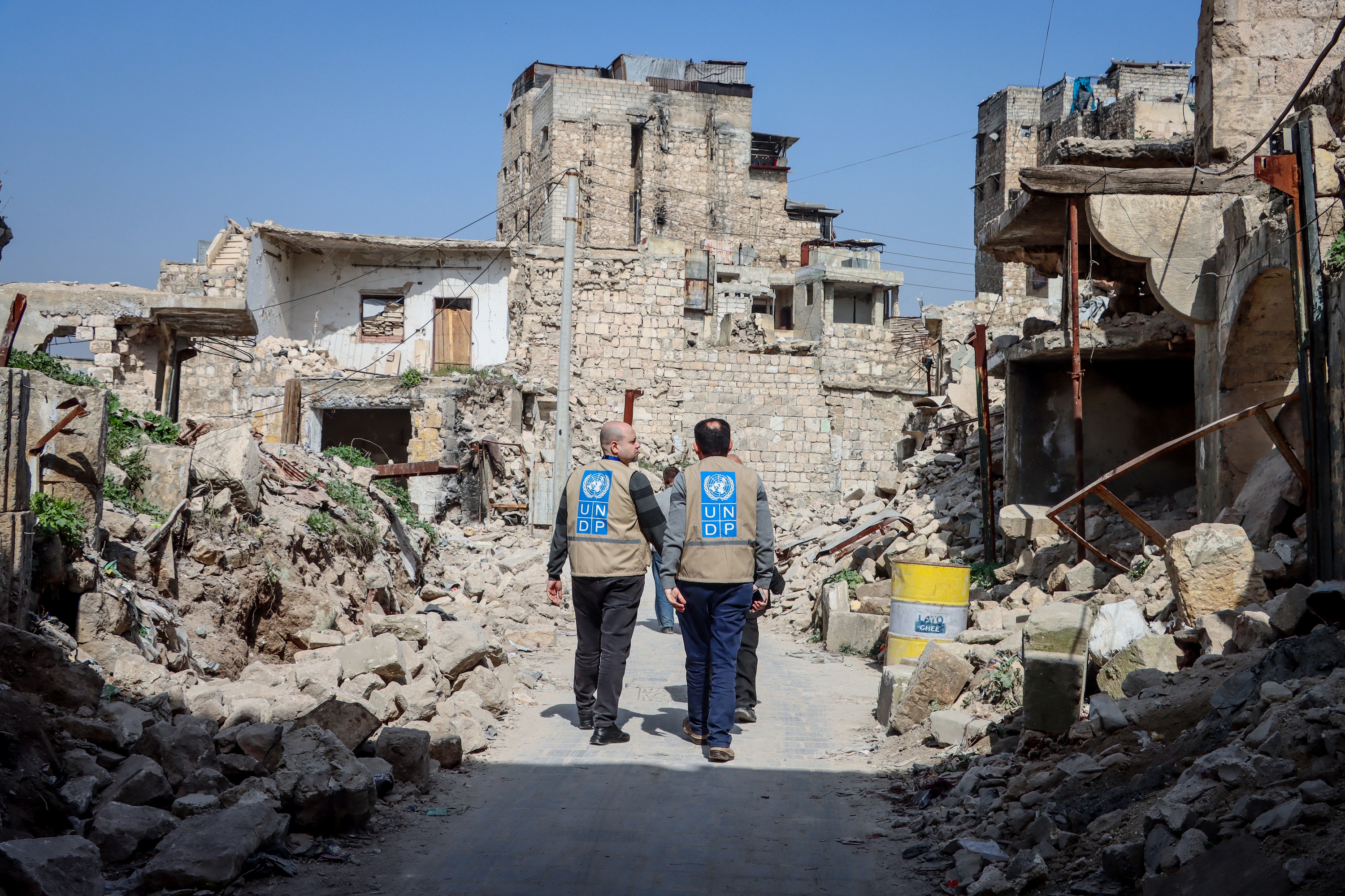 Two UNDP team members walk through rubble-filled street in Aleppo's old ...