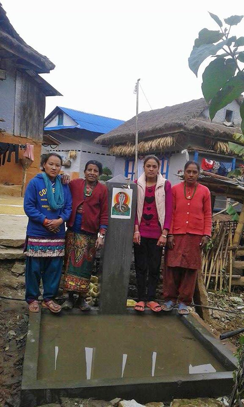 The all-women-construction-committee poses proudly in front of a recently completed tap in Maheswori.