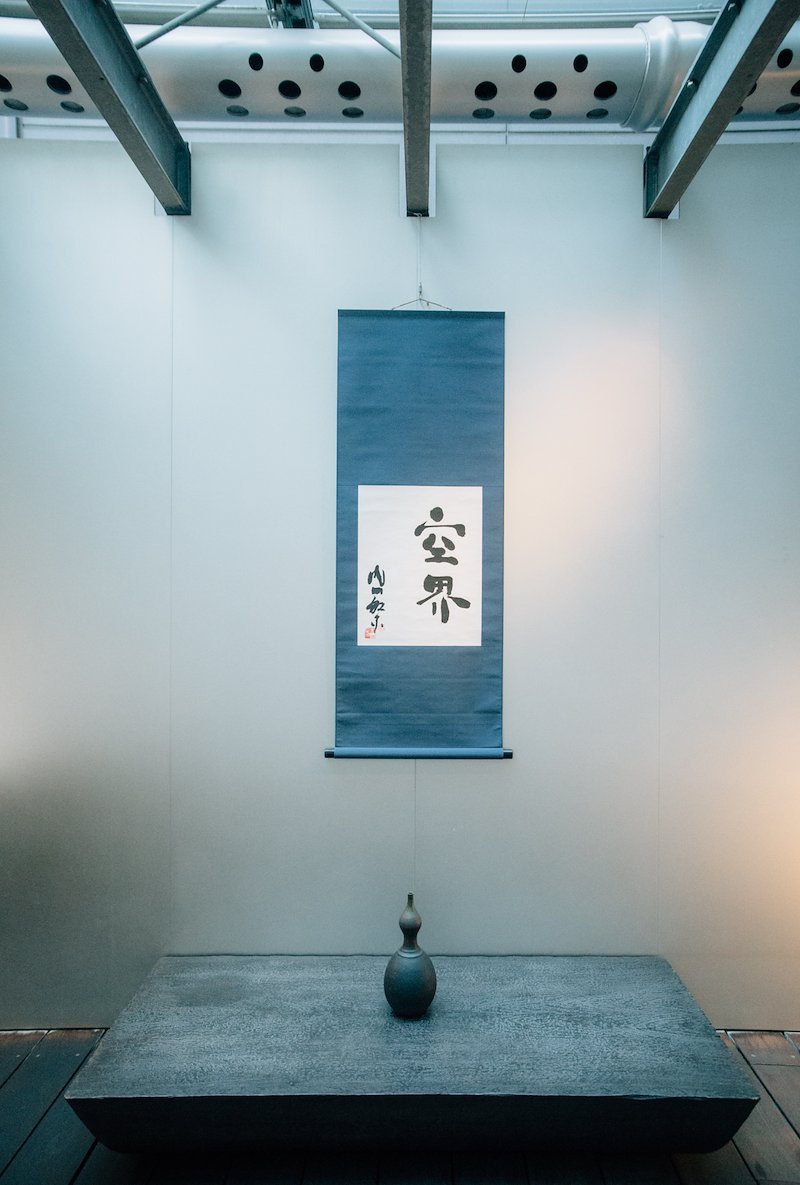 A hanging scroll and vase on display.