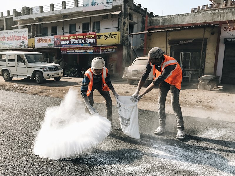 Workers finishing new asphalt outside Rishikesh.