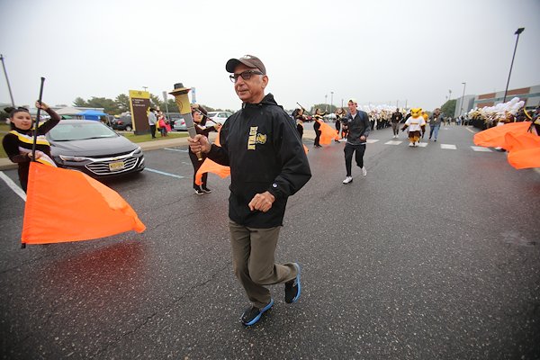 Running to the marching band's beat, President Ali A. Houshmand delivered the torch to the celebration area.