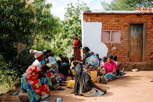 Mayamiko from CURE Malawi's spiritual department prays with patient Flora's village.