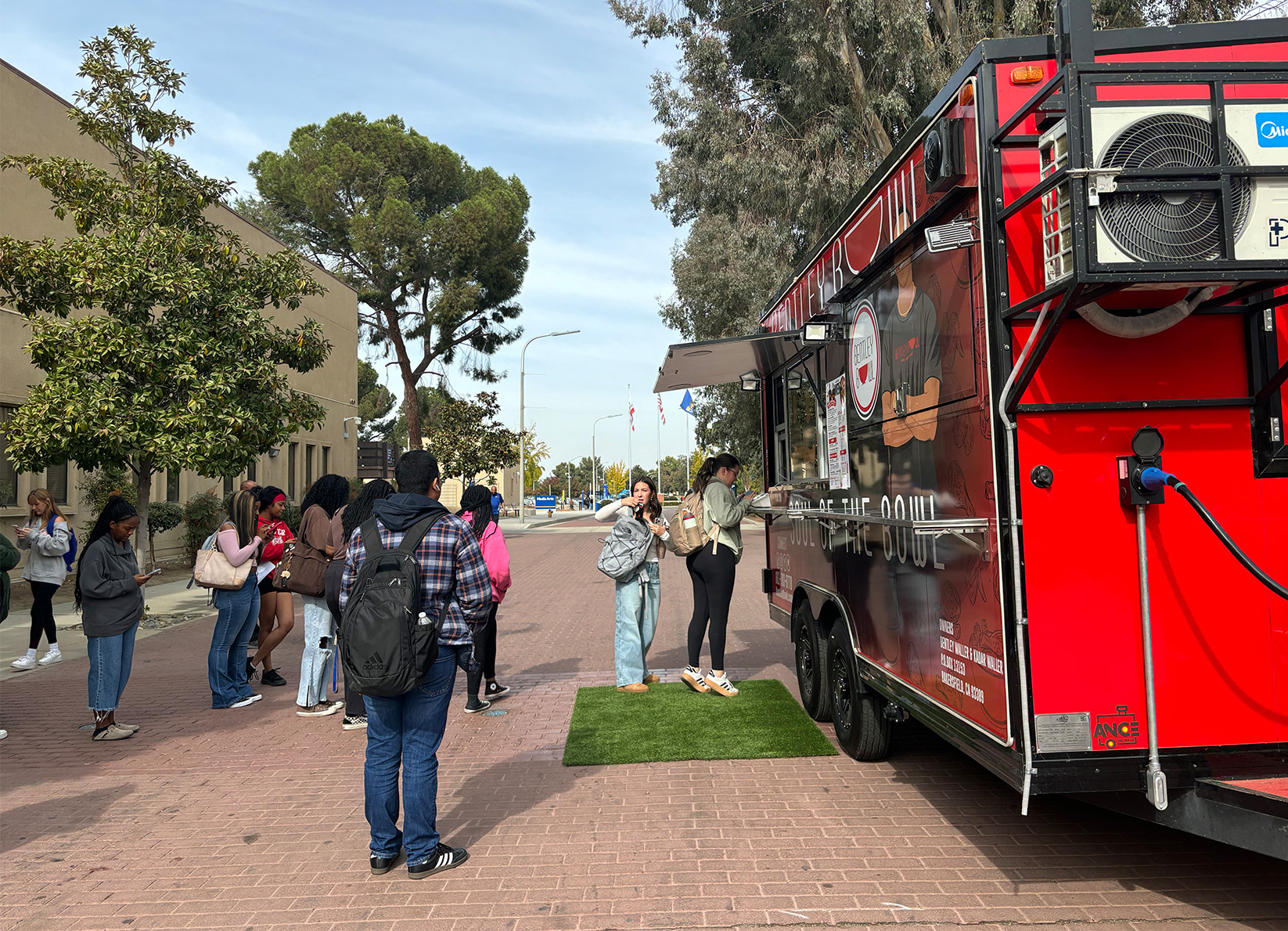Students line up to get food from the Bentley Bowl truck during a stop ...