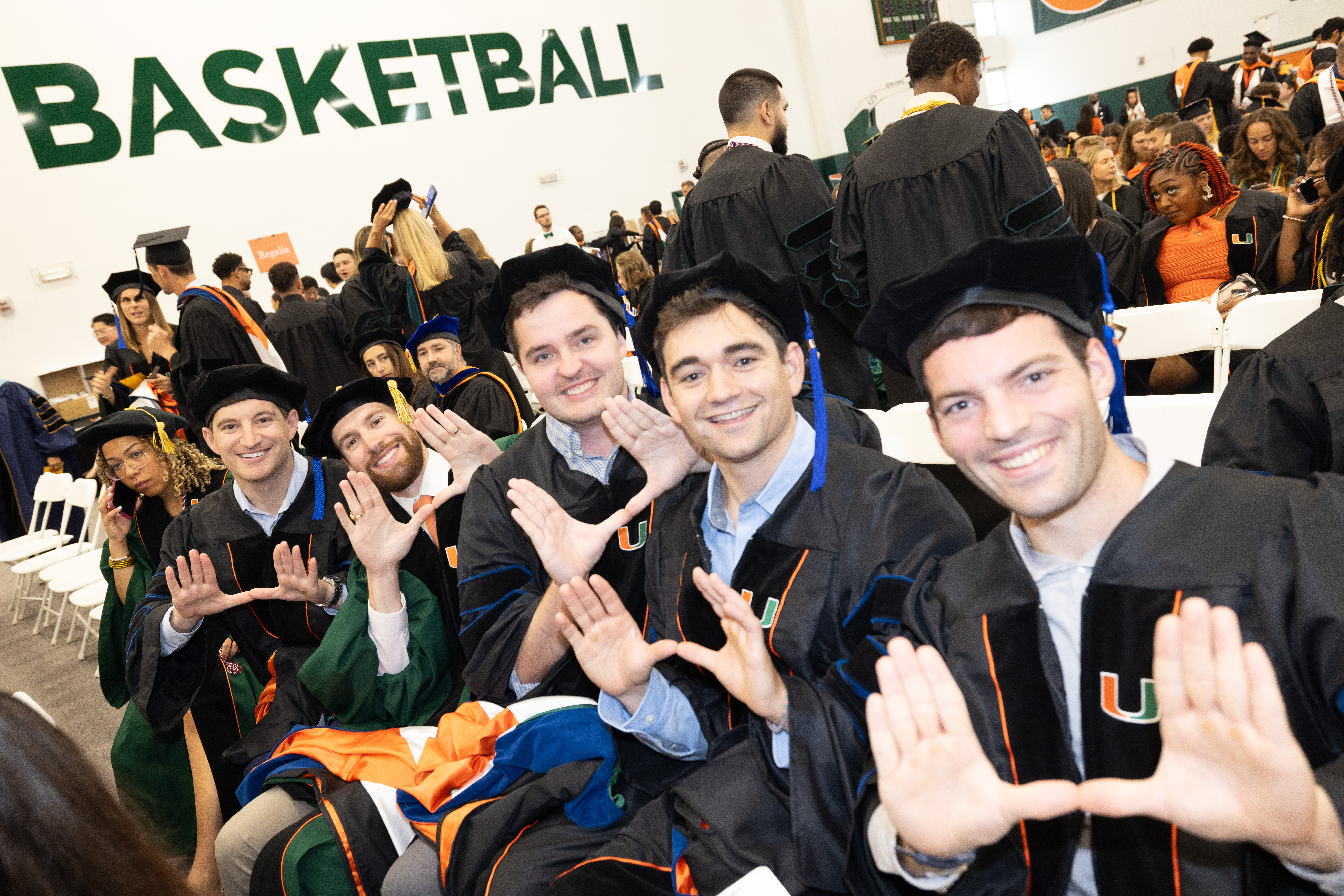 Smiling graduates in caps and gowns make the