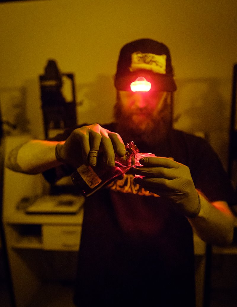 CJ Harker wears a red headlamp to begin the tintype developing process.