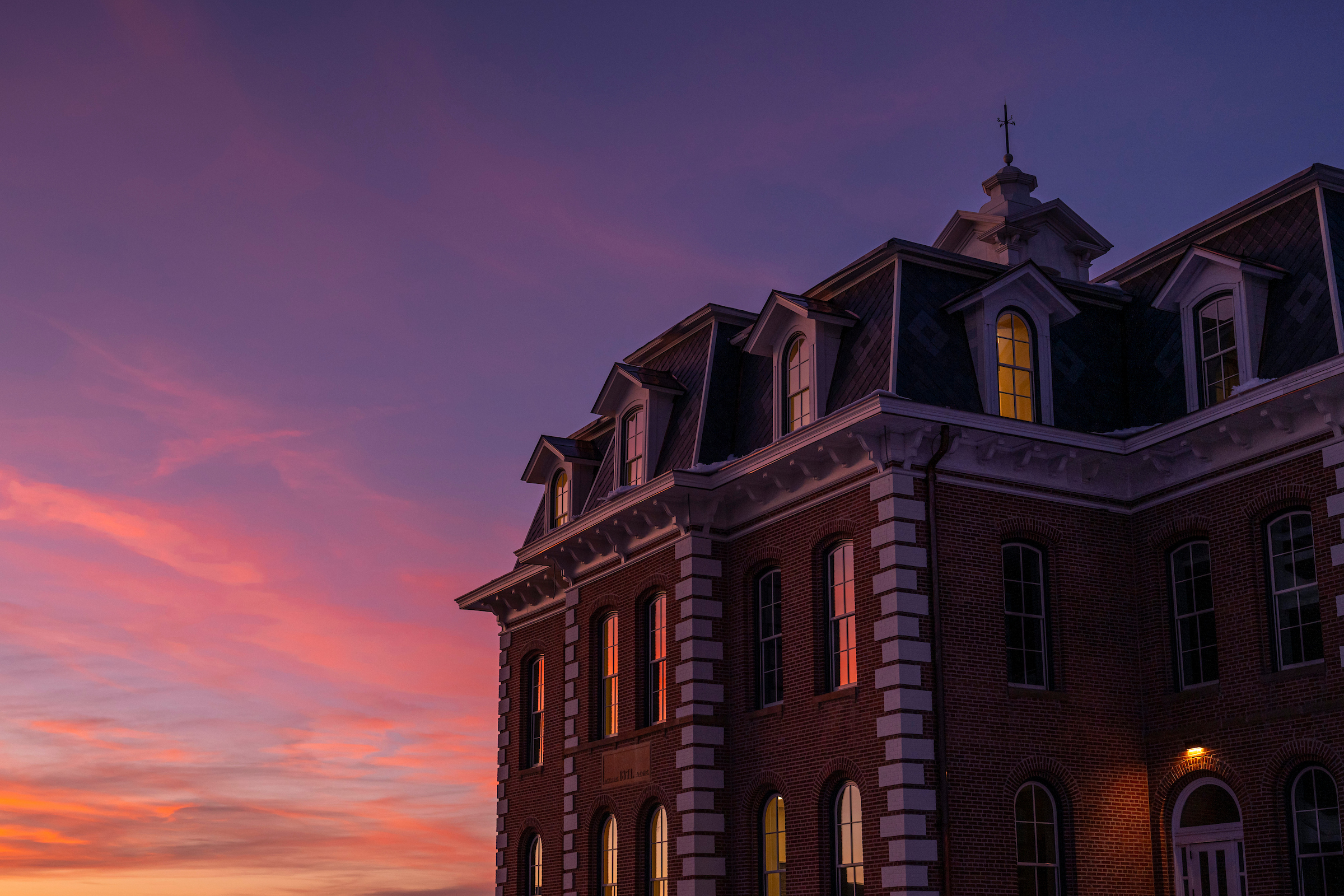Brick building with white trim under a vivid pink and purple sunset sky ...