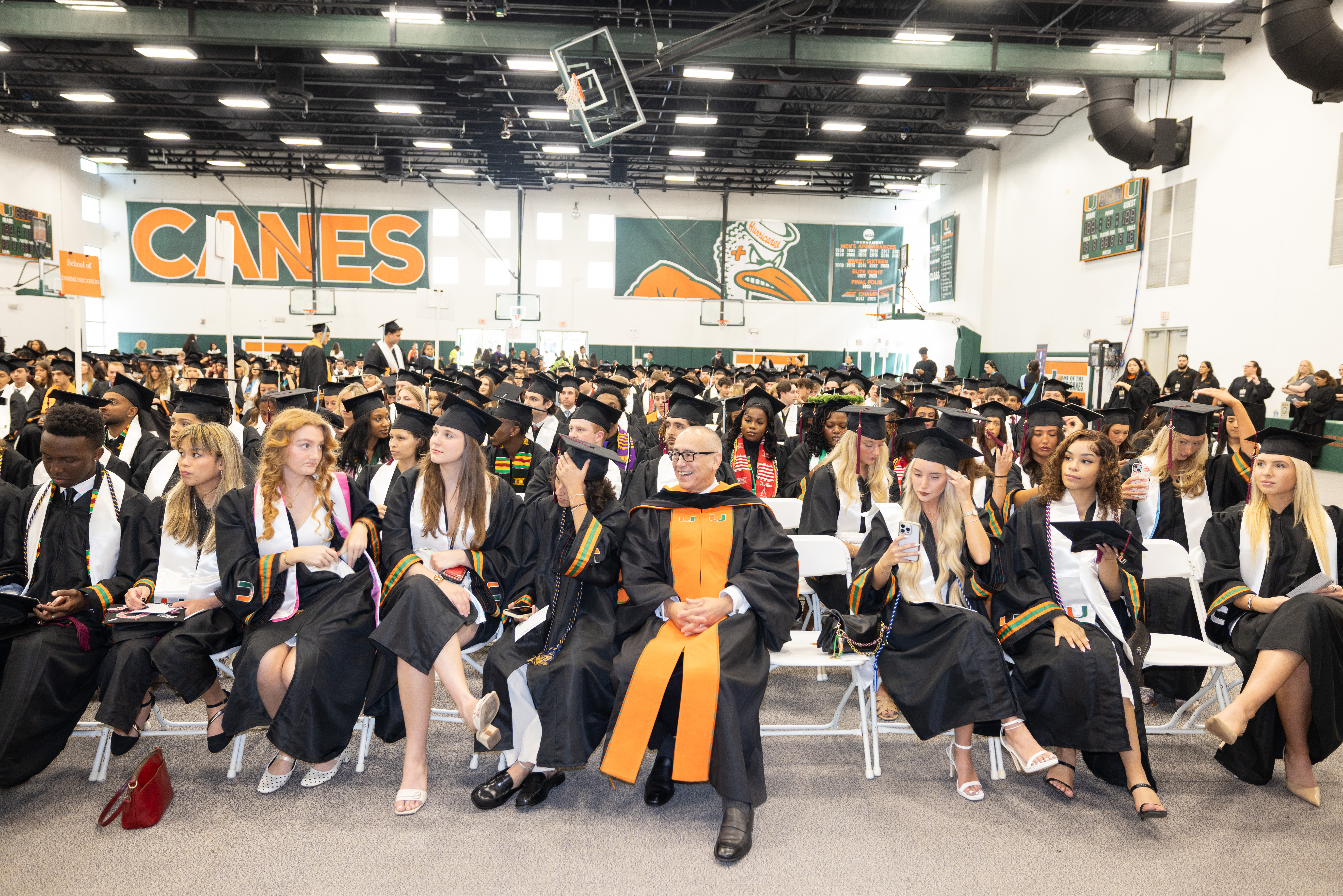 Graduates in black gowns and caps sit in rows at the Spring 2026 ...